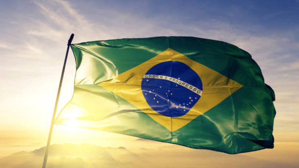 Brazil Brazilian flag on flagpole textile cloth fabric waving on the top sunrise mist fog